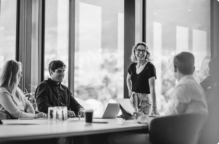 A few people in a conference room laughing and having a good time working.