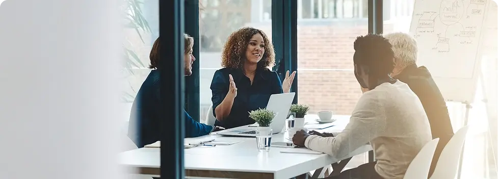 Colleagues discussing documents around a meeting table.