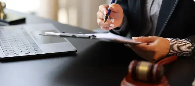 A person reviewing documents beside a laptop and gavel.
