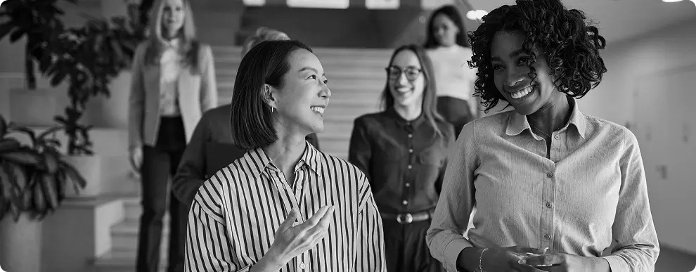 Colleagues talking as they walk through an office.