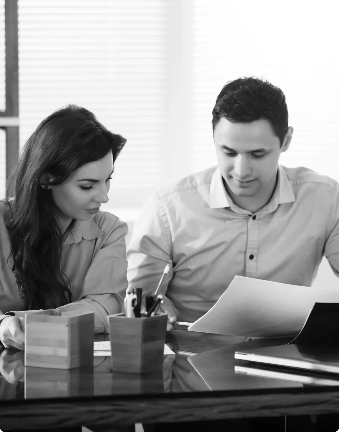 Two people reviewing paperwork together at a desk. 1-3