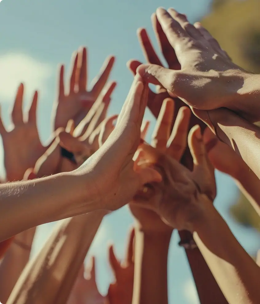 A group of people bringing their raised hands together.
