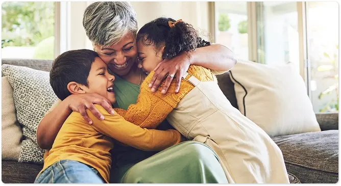 An older woman hugging two children on a sofa.